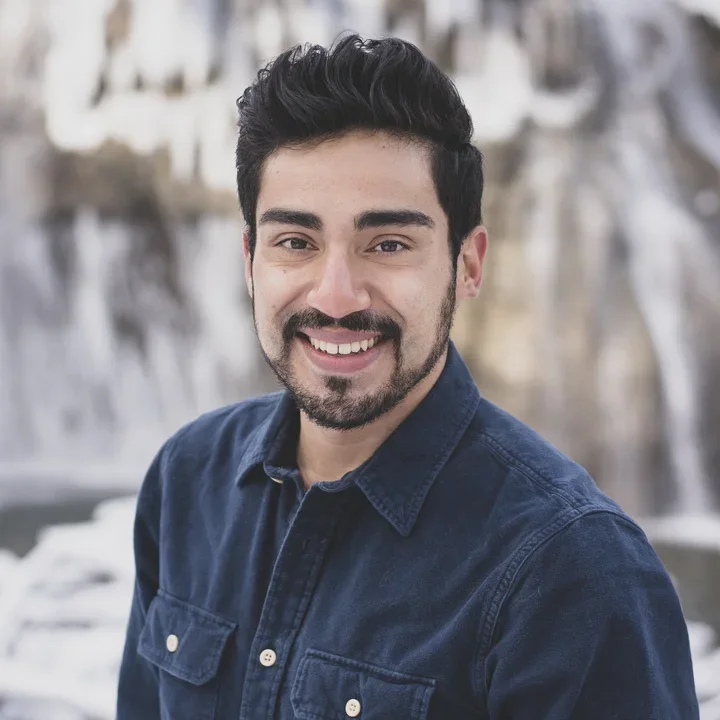 Julio Sanchez's professional headshot, wearing a dark blue collared shirt in front of a grey background.